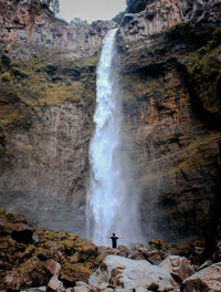 Man standing against waterfall