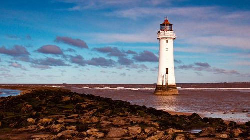 Lighthouse by sea against sky