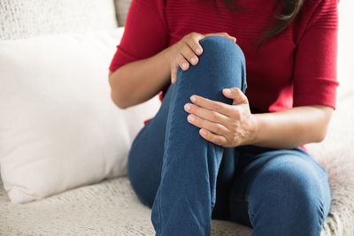 Midsection of woman sitting on sofa at home