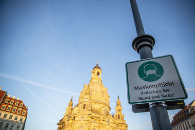 Low angle view of road sign against blue sky