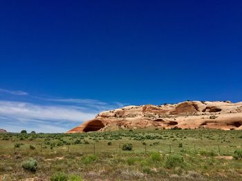 Rock formations on landscape against blue sky