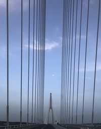 Low angle view of suspension bridge against cloudy sky