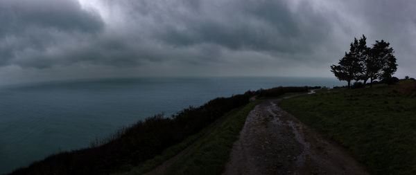 Road amidst trees and sea against sky