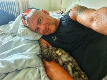 Portrait of mature man lying down with cat at home