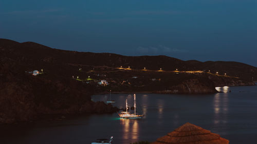 Illuminated bridge over river against sky at night