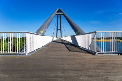 Empty footbridge against clear blue sky