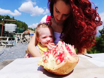 Woman feeding pomegranate to baby girl