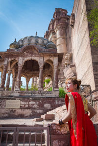 Woman in red sari standing against temple