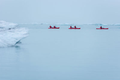 Man paddling in a kayak in the freezing waters of jokulsarlon glacier lagoon between icebergs