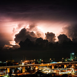 Illuminated city against sky at night during thunderstorm 