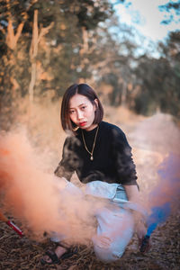 Portrait of woman holding distress flare in forest