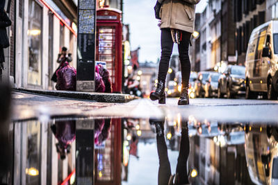 Low angle view of woman standing on street in city