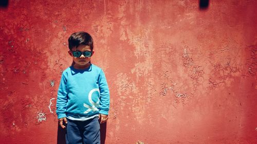 Portrait of a young boy against red wall