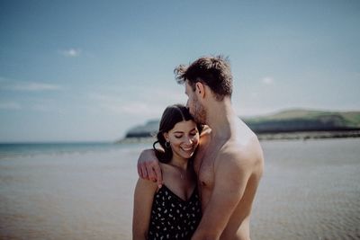 Friends enjoying at beach against sky