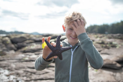 Boy holding starfish at beach