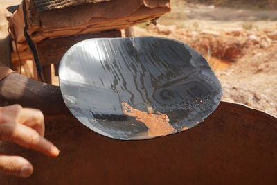 Cropped hand of person holding metal plate over container