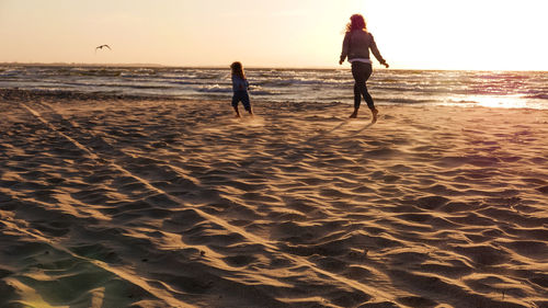 Mom and daughter are running on the beach