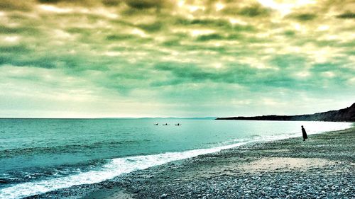 Scenic view of beach against cloudy sky