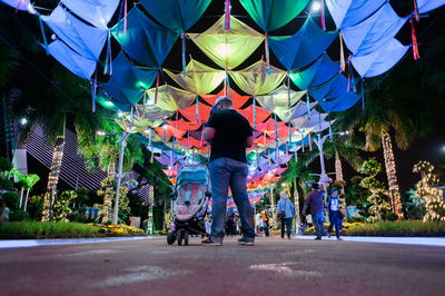 People on street under multi colored decorations at night