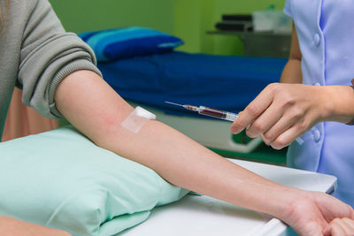 Midsection of female doctor injecting patient at hospital