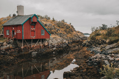 House by lake and buildings against sky