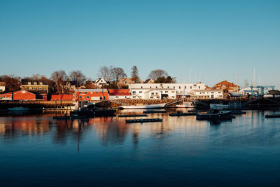 Boats moored at harbor against clear blue sky