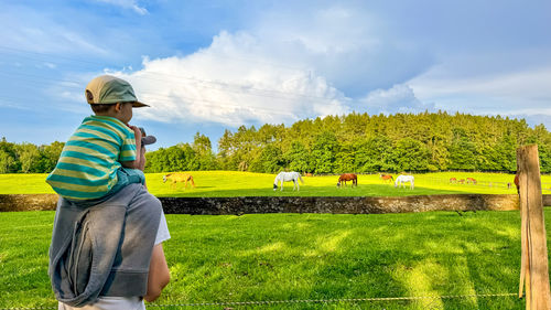 Rear view of woman standing on field against sky