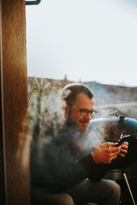 Man looking at camera while sitting on mobile phone