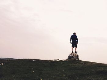 Rear view of man standing on mountain against sky