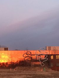 Metal fence on field against sky at sunset