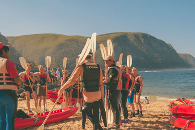 People at beach against clear sky