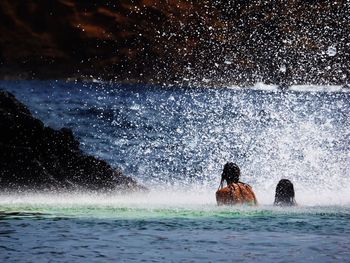 Rear view of women in sea at porto moniz