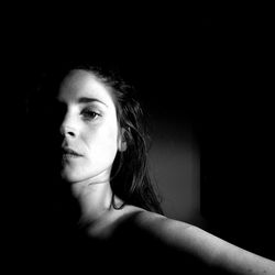 Close-up portrait of young woman against black background