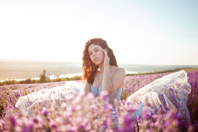 A beautiful young girl against the sunset and a beautiful sky in a lavender field. 