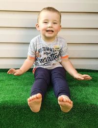 Portrait of cute smiling boy sitting on green rug