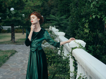 Woman looking away while standing against plants