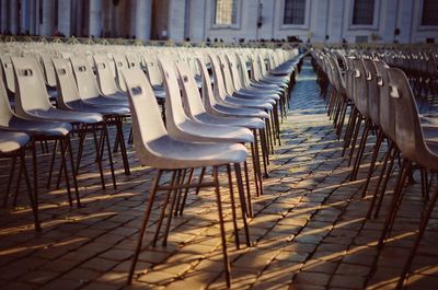 Empty chairs on footpath in city