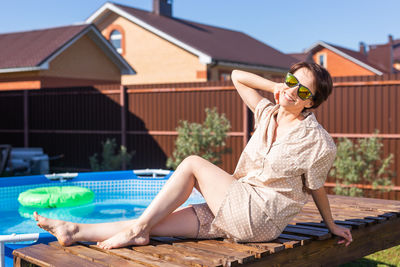 Portrait of young woman sitting at poolside