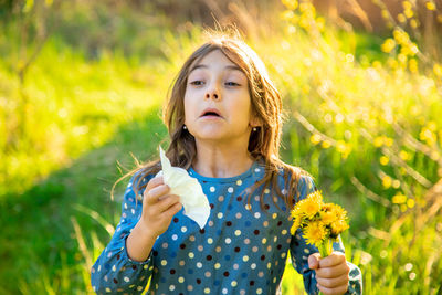 Girl holding flower sneezing in garden