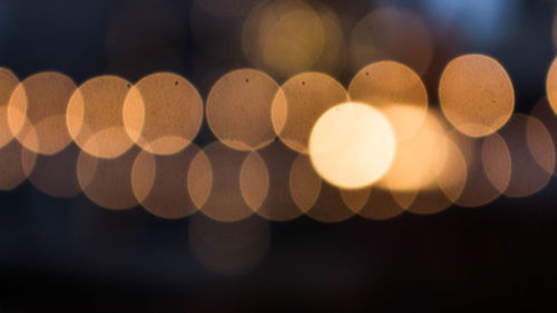 Close-up of illuminated lights against sky at night