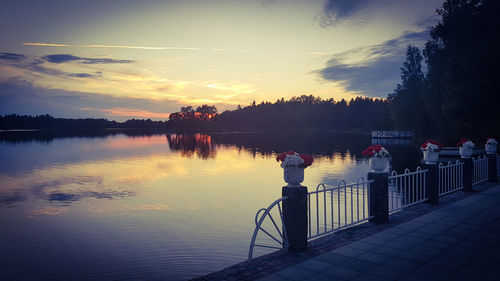 Silhouette people by lake against sky during sunset