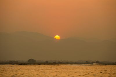 Scenic view of silhouette mountain against orange sky