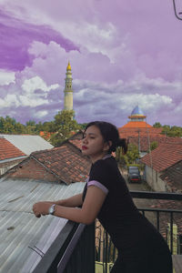 Woman standing by building against sky