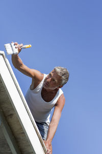 Mature man painting gable, sweden