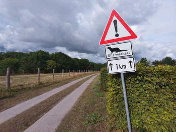 Information sign by road against sky