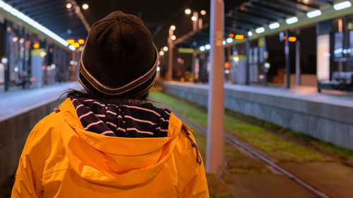 Rear view of woman standing at illuminated railroad station