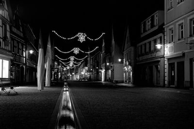 Illuminated street light against building at night