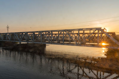 Bridge over river against sky during sunset