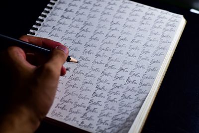 Close-up of hand writing in book at table