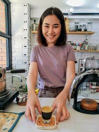 Portrait of a smiling young woman in kitchen at home